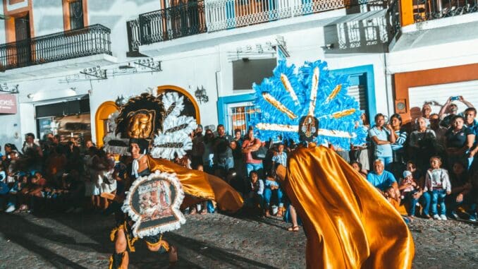 Vibrant street parade with colorful costumes and dancers in Puerto Vallarta, Mexico.