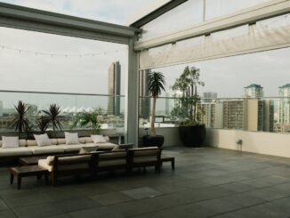 Spacious rooftop patio with modern furniture overlooking a city skyline.