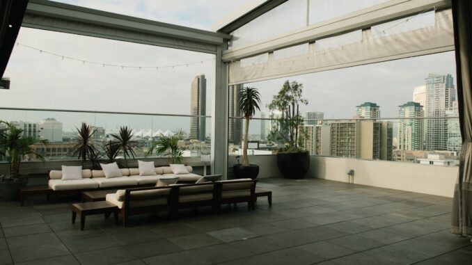 Spacious rooftop patio with modern furniture overlooking a city skyline.