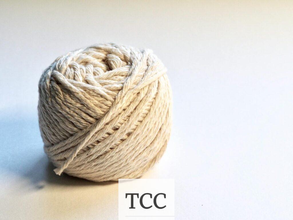 Detailed close-up of a natural cotton yarn ball on a white background, perfect for textile and crafting themes.